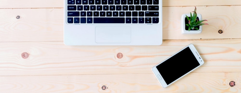 Clavier, plante et smartphone posés sur une planche en bois